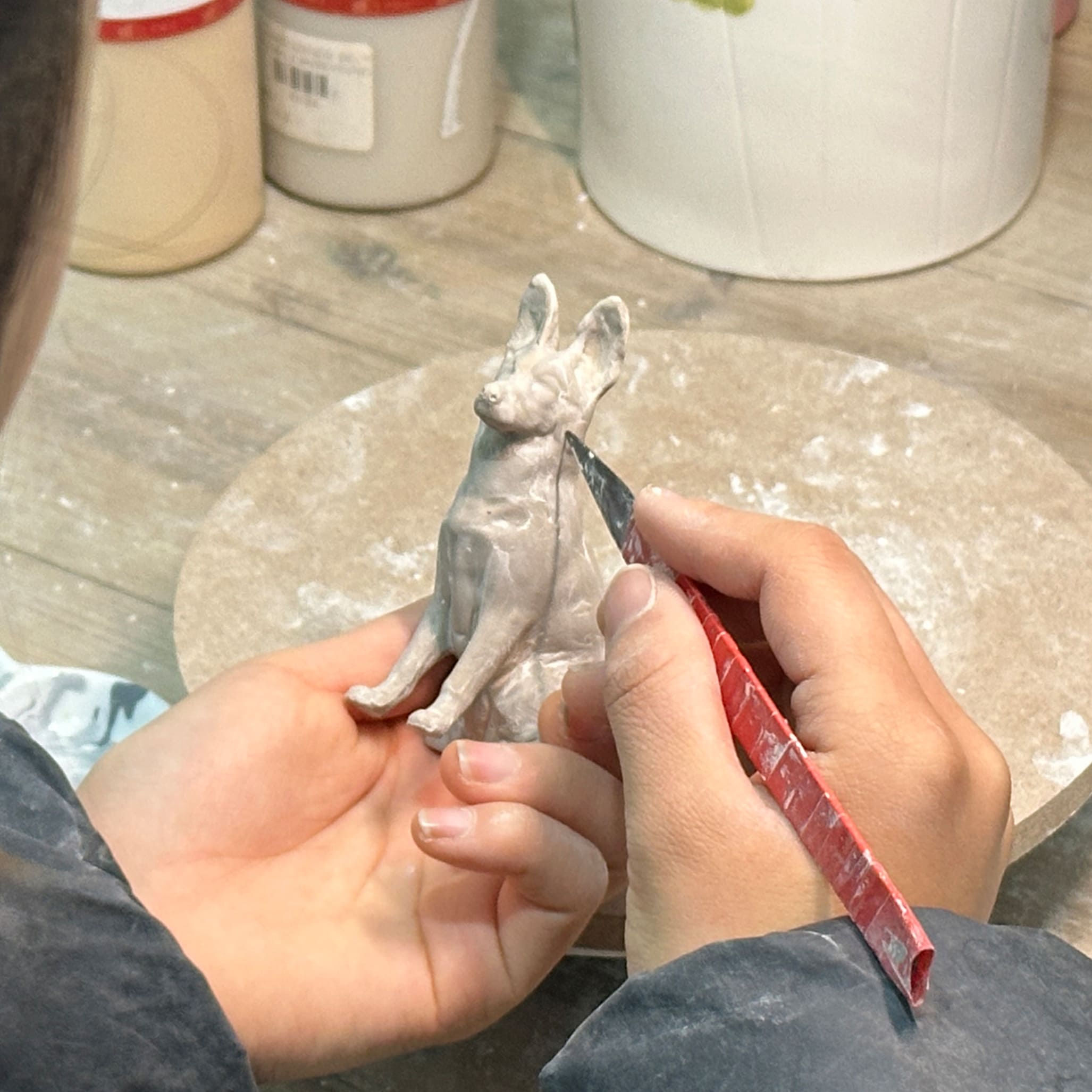 Dog figurine sculpture being shaped by hand, for a custom pet urn