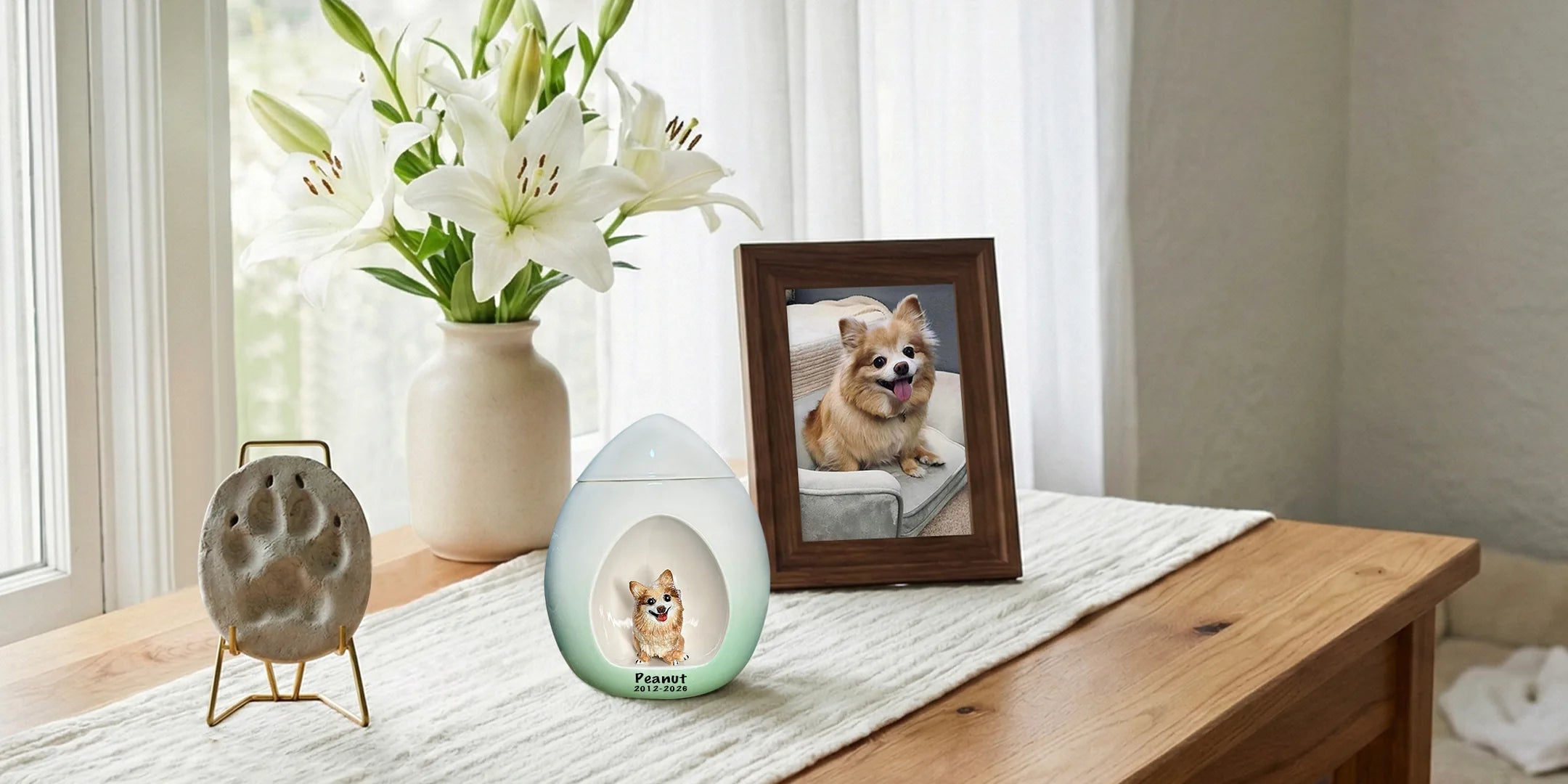 Custom ceramic dog urn displayed beside a framed pet photo and paw print keepsake in a bright home memorial setting