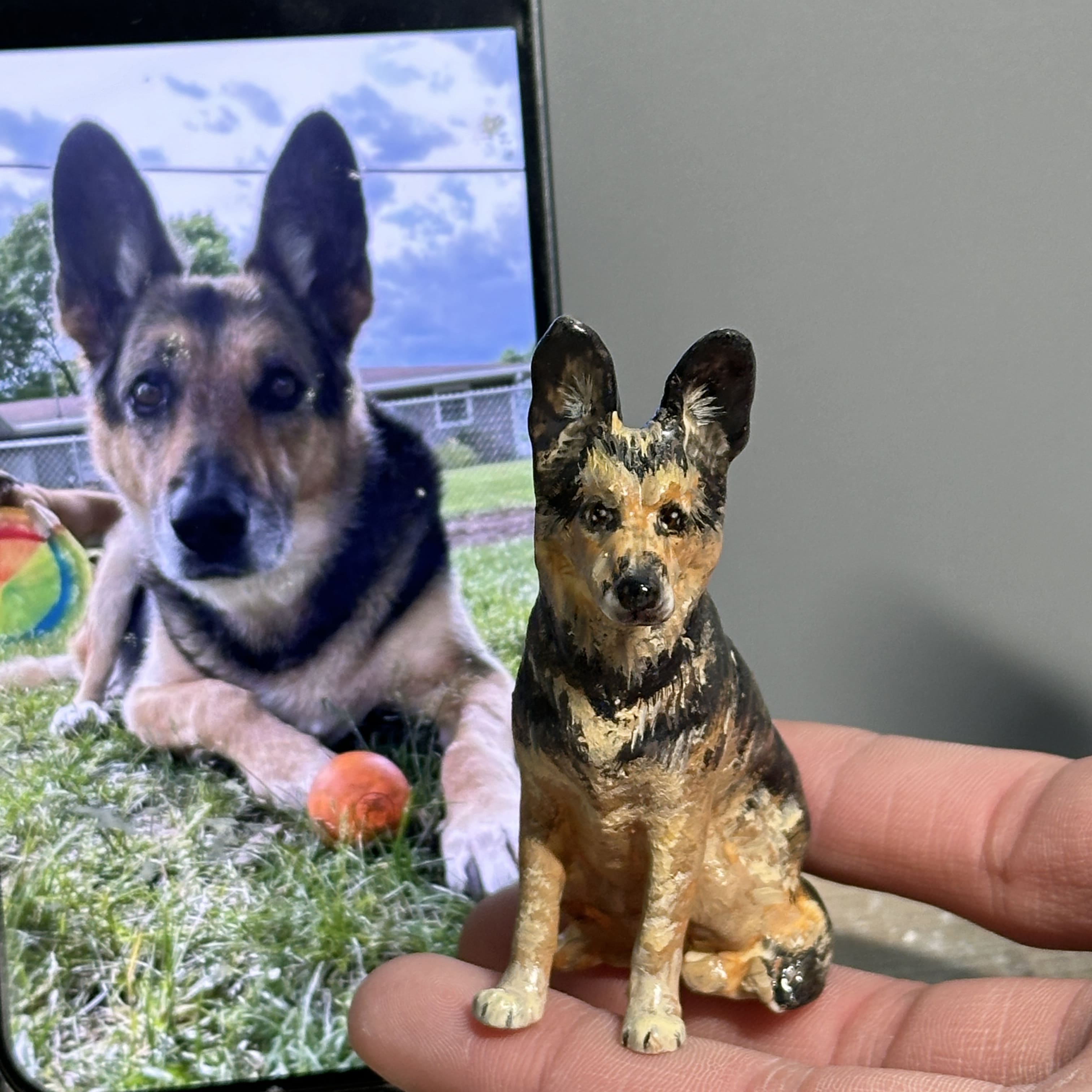 Ceramic dog figurine being painted, brown-and-black seated dog statue
