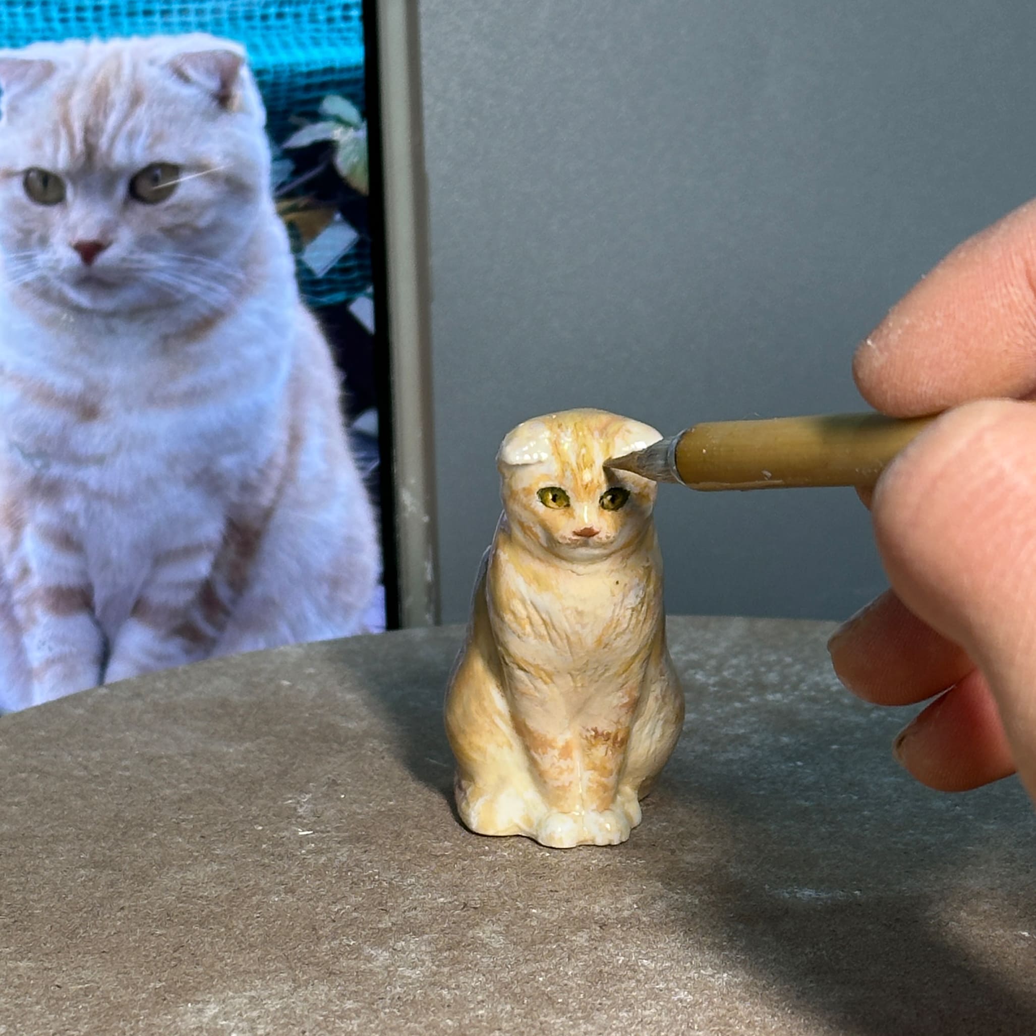 Painted sculpted cat figurine, small cream and tan cat figure on work surface
