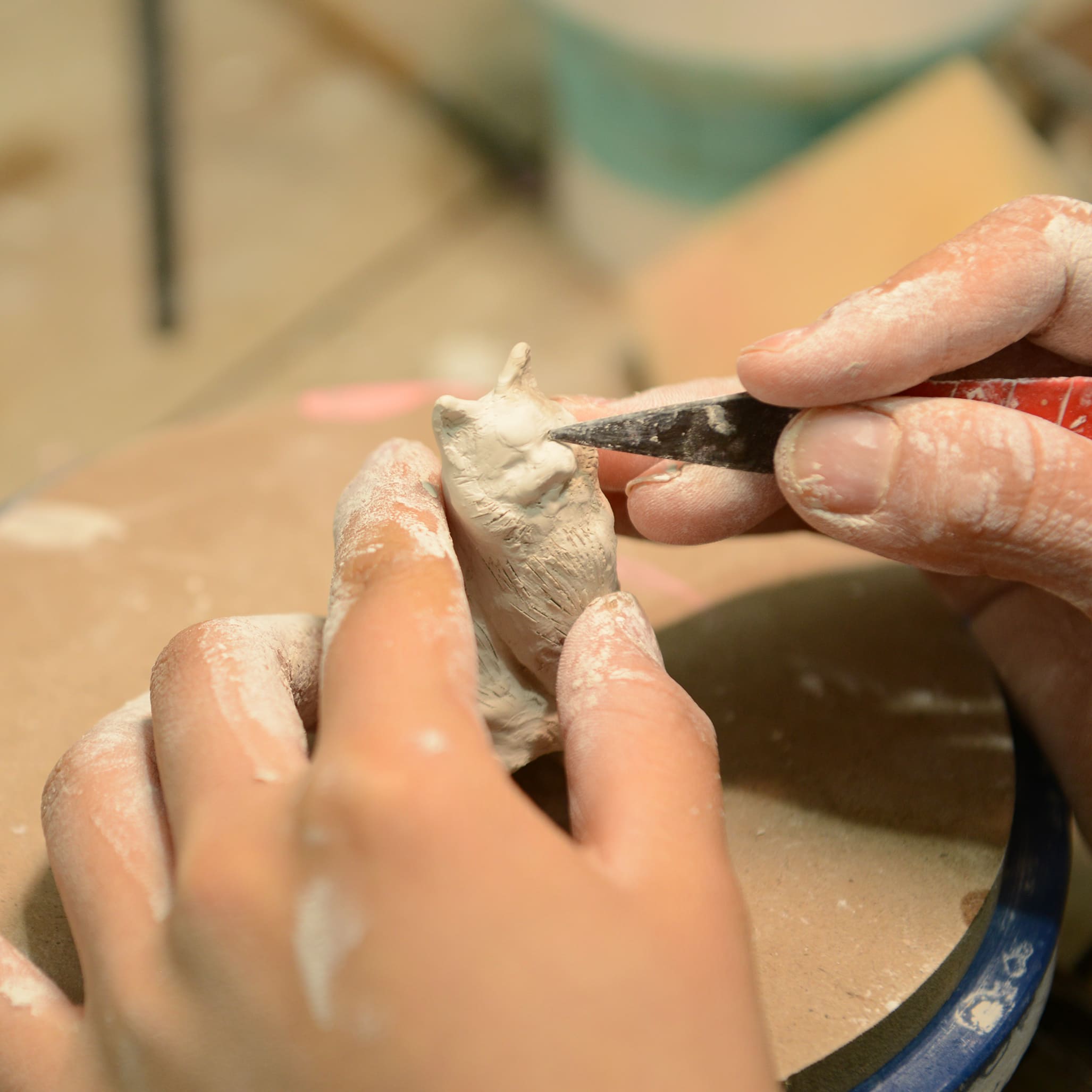 Sculpting a cat figurine from clay by hand, small detailed head and body