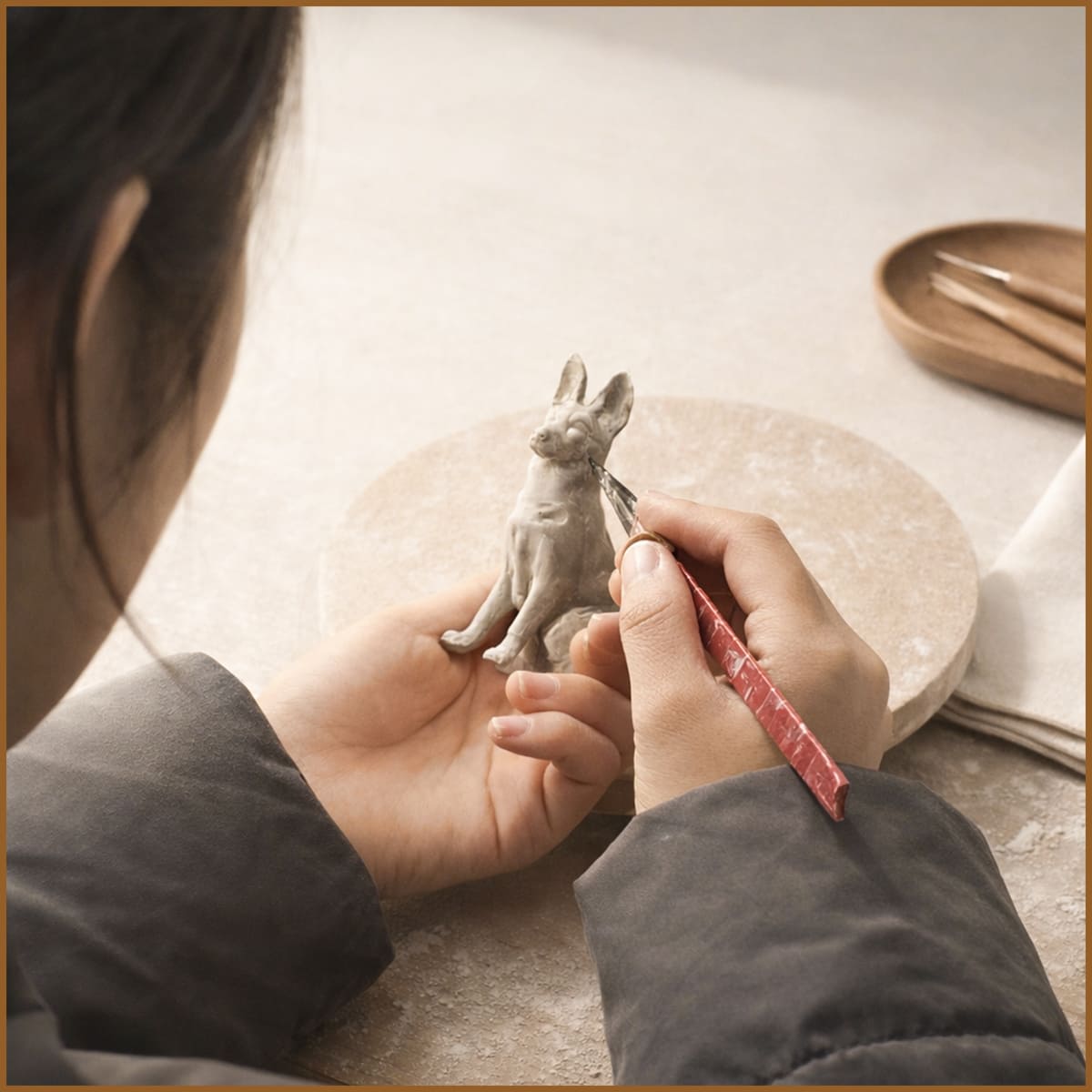 artist hand sculpting a dog figurine in clay for a custom ceramic pet urn