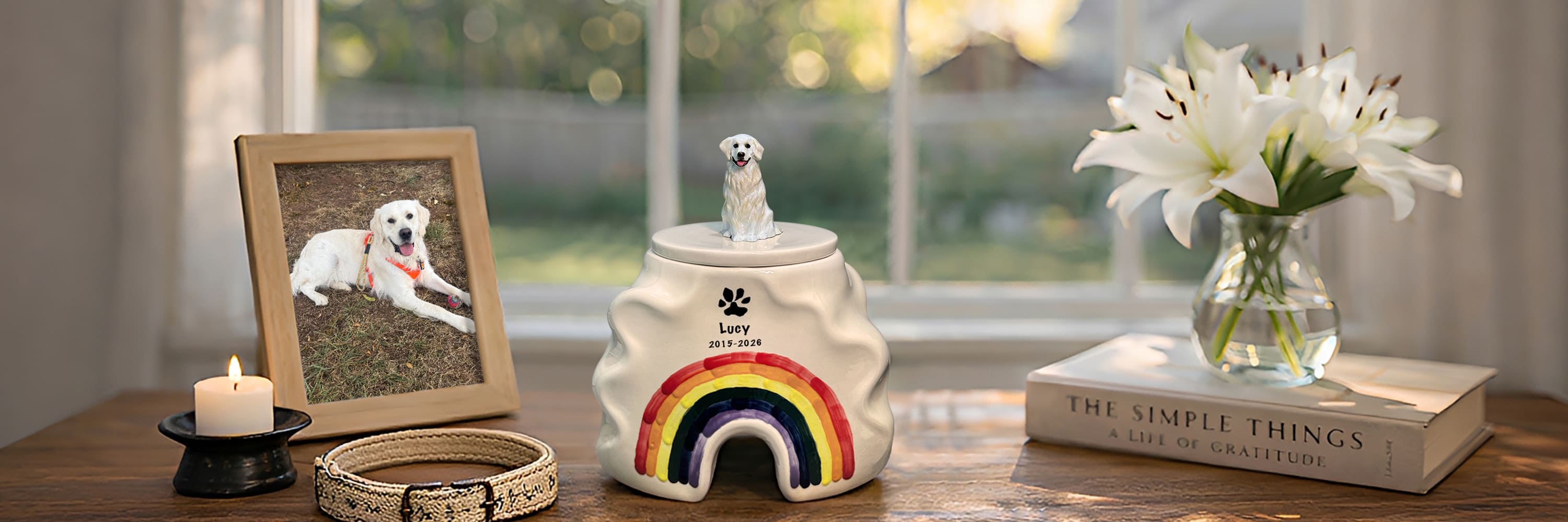 Rainbow bridge pet urn with dog figurine displayed on a memorial table with pet photo candle and collar